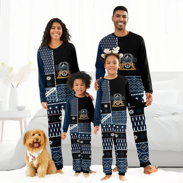 Smiling family in matching black and navy Modelo logo pajamas with winter patterns, standing in bright bedroom with dog