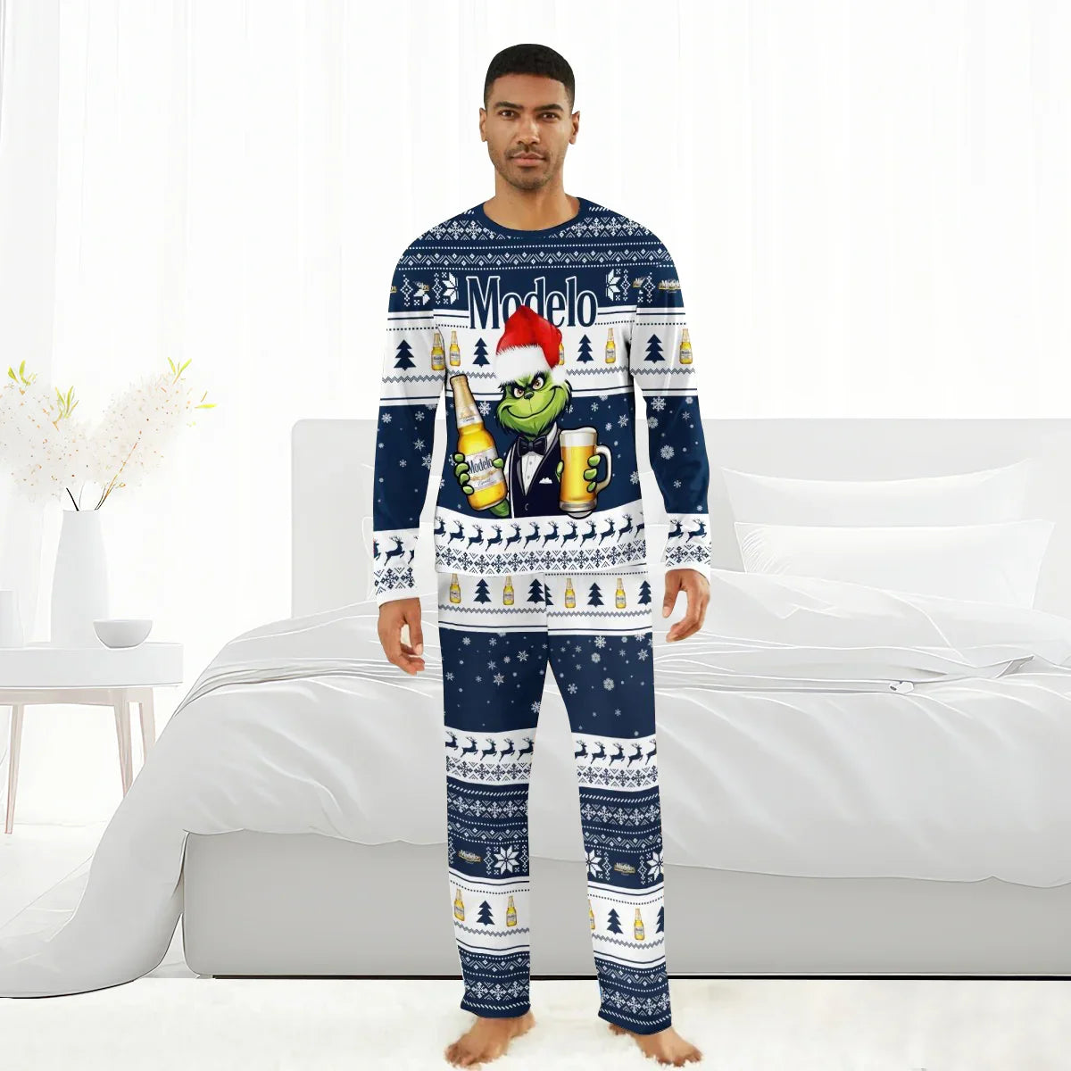 Man wearing navy blue Modelo Grinch Christmas pajamas with holiday patterns in a white bedroom