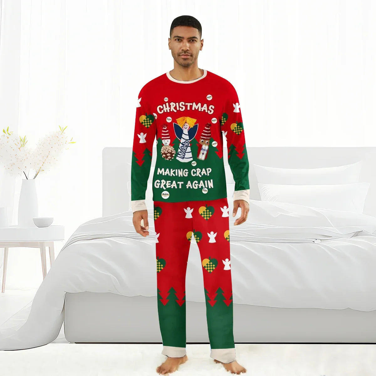 Man in festive red and green Christmas pajamas with Modelo beer bottle and holiday icons standing barefoot in a white bedroom