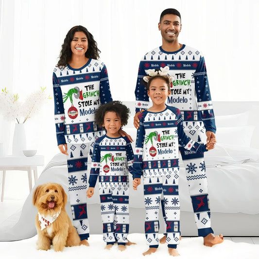 Smiling family in matching Christmas pajamas with The Grinch stole my Modelo design, standing in bright bedroom