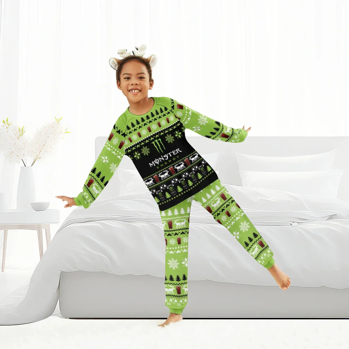 Smiling child wearing green Monster Energy Christmas pajamas in bright bedroom with white bed and decor