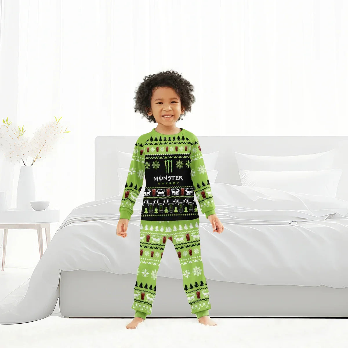 Smiling child in green Monster Energy Christmas-themed pajamas standing barefoot in modern white bedroom
