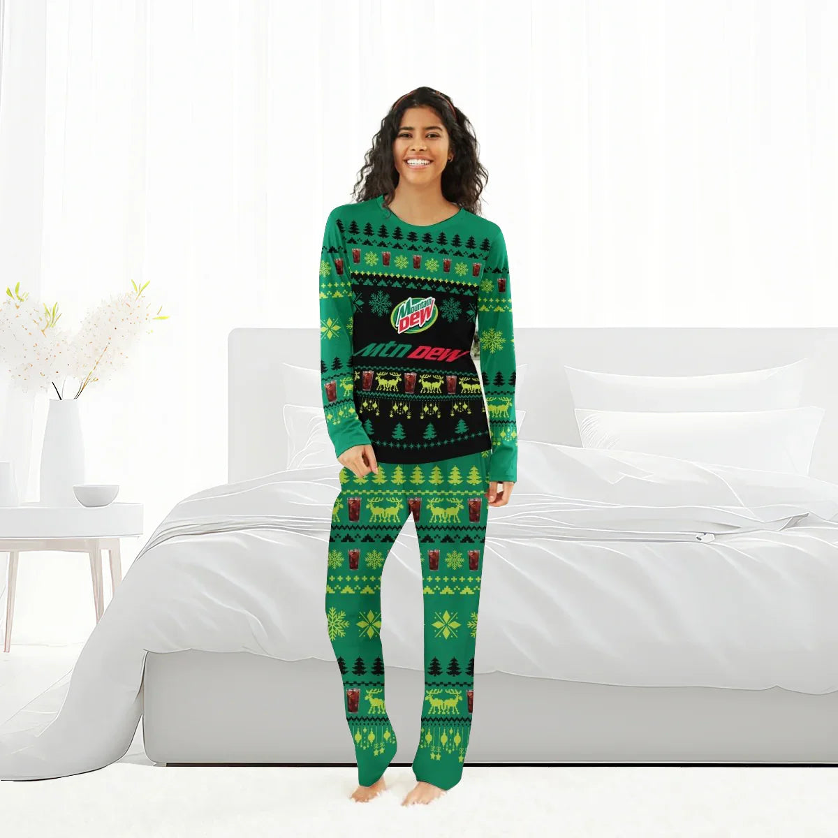Smiling woman in green Mountain Dew Christmas pajamas standing barefoot in modern white bedroom