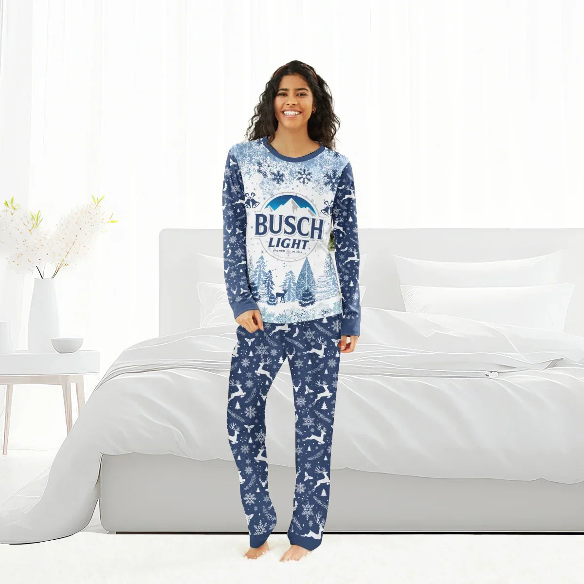 Smiling woman wearing blue Busch Light Christmas pajama set with snowflake and reindeer patterns in bright bedroom