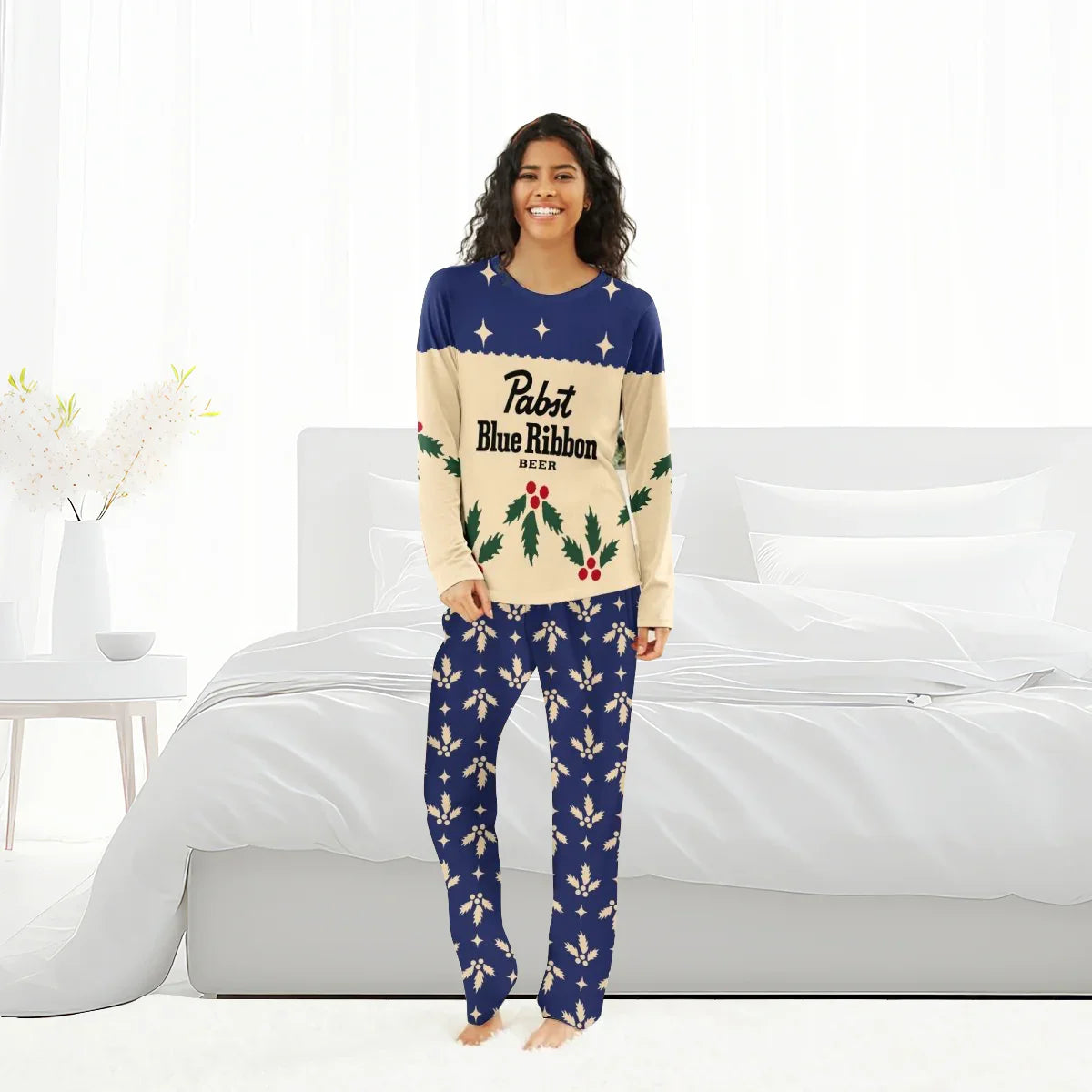 Smiling woman in Pabst Blue Ribbon Christmas cherry holiday pajamas set standing barefoot in bright bedroom
