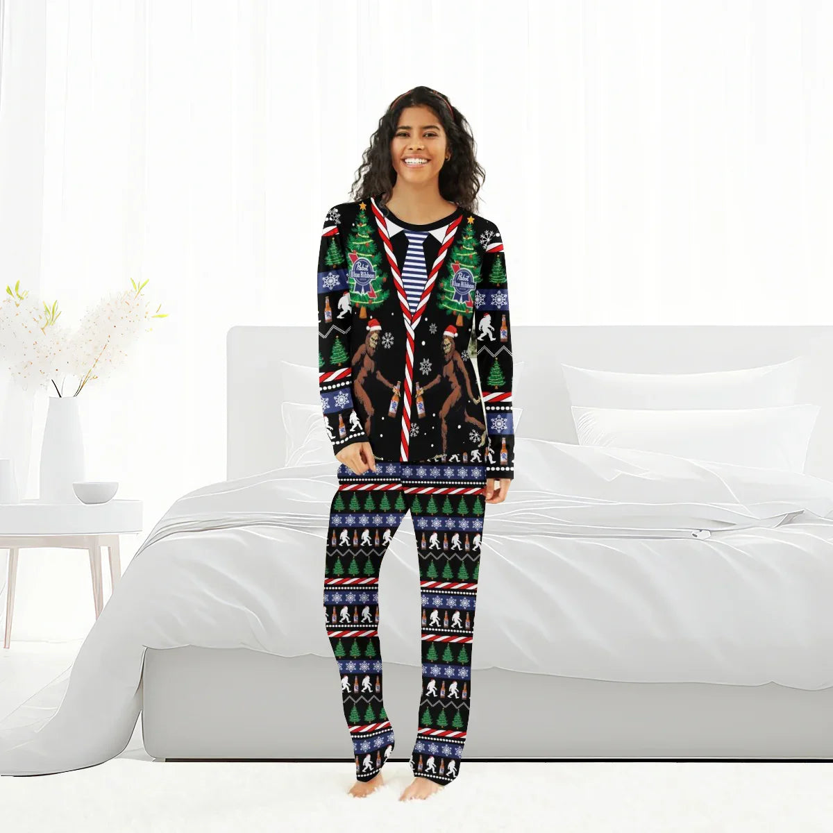 Smiling woman wearing Pabst Blue Ribbon Christmas Bigfoot family pajamas standing in a bright bedroom