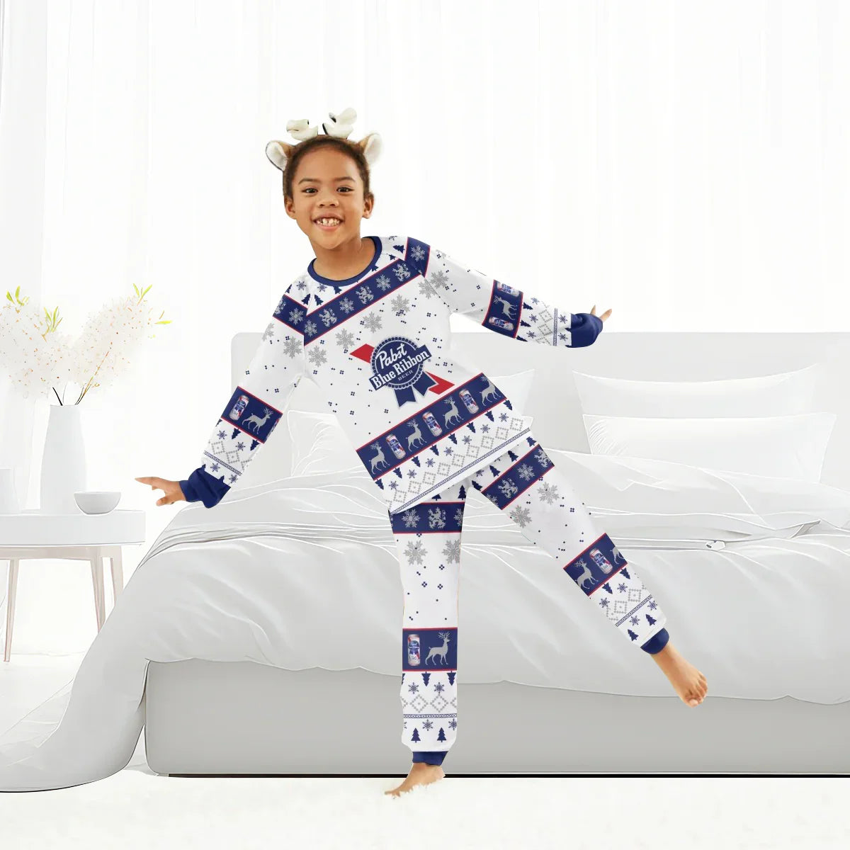 Smiling child wearing Pabst Blue Ribbon Christmas-themed pajamas in bright modern bedroom