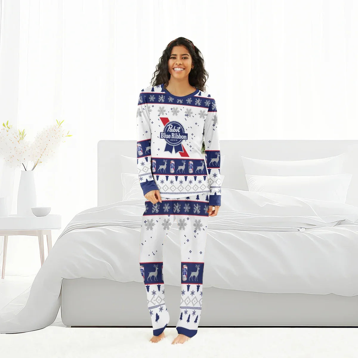 Woman wearing Pabst Blue Ribbon holiday-themed pajamas with snowflakes, reindeer, and beer can designs in bright bedroom
