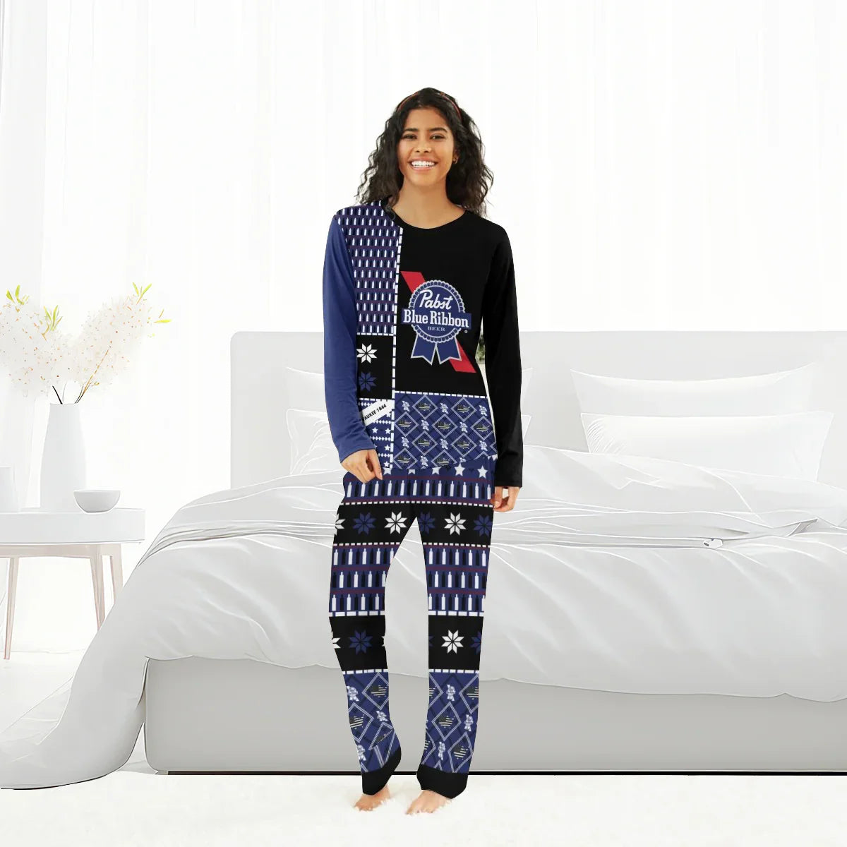 Smiling woman wearing Pabst Blue Ribbon themed family pajamas in a bright bedroom