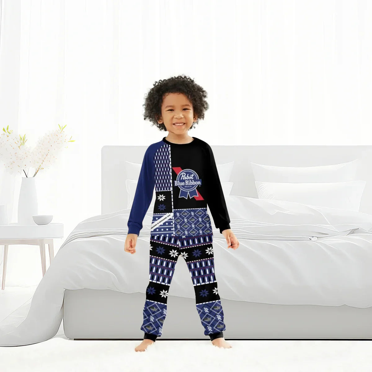 Smiling child wearing blue and black Pabst Blue Ribbon family pajamas in modern white bedroom