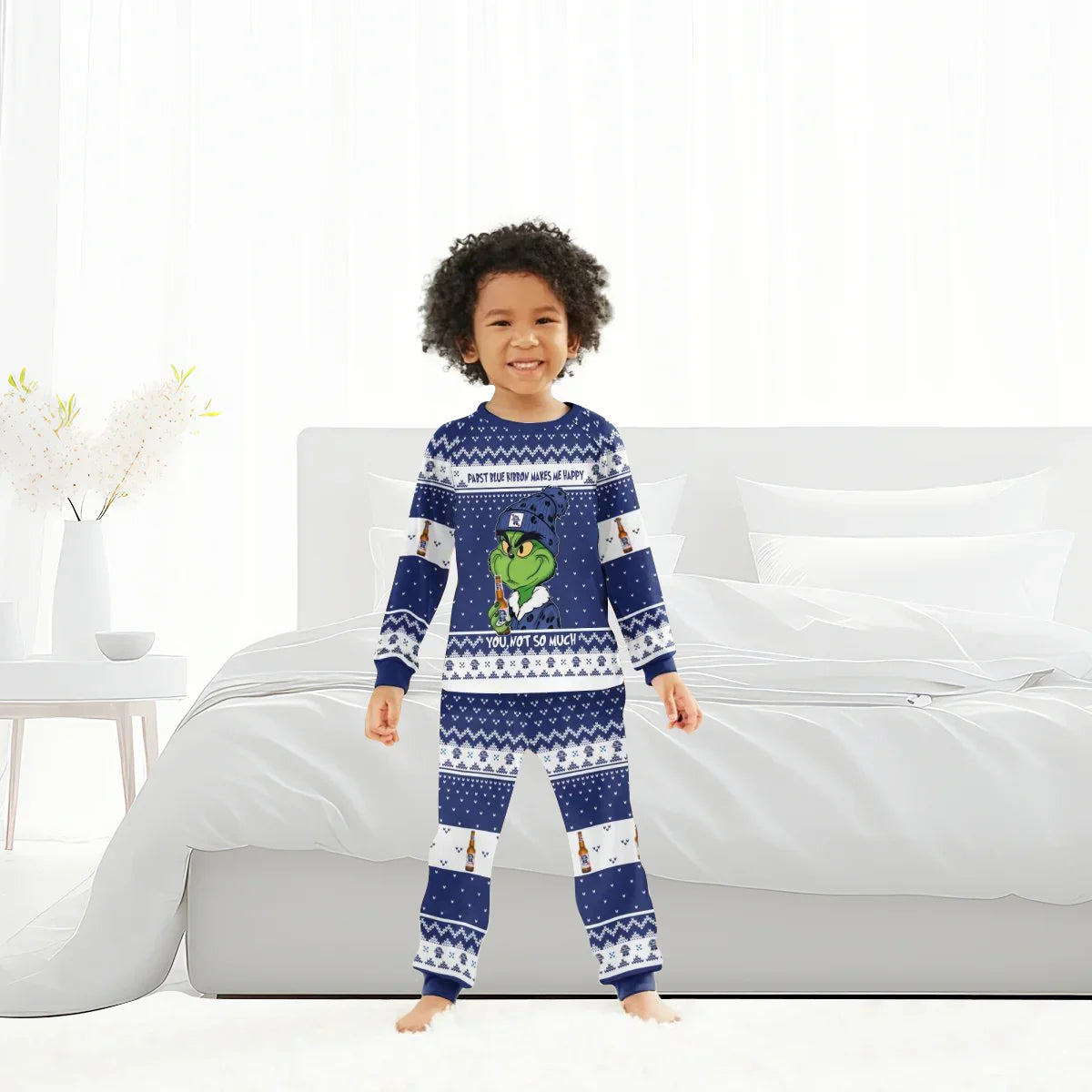 Child wearing blue Grinch-themed family pajamas with Pabst Blue Ribbon design in bright bedroom