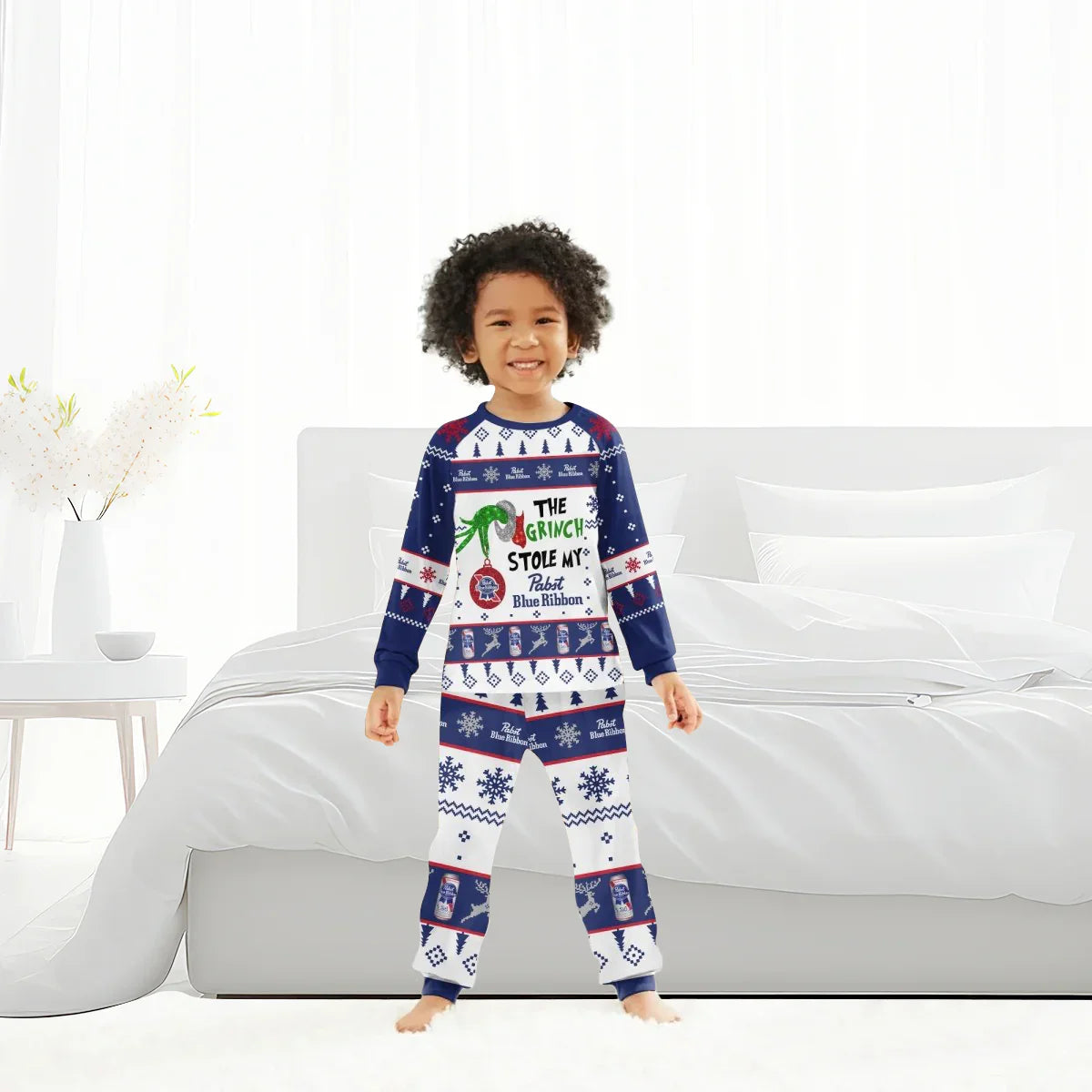 Smiling child wearing blue and white Grinch-themed Pabst Blue Ribbon holiday pajamas in modern bedroom