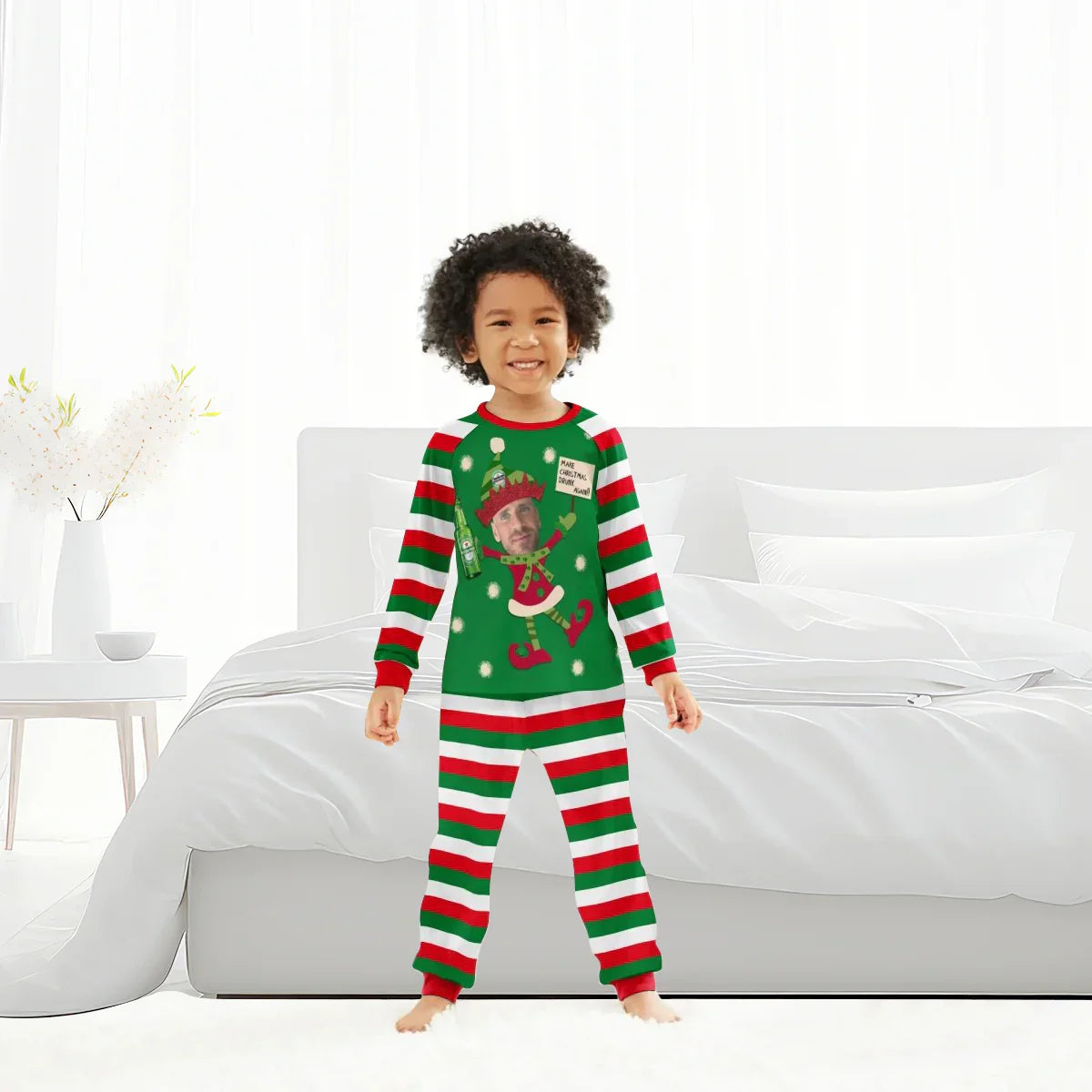 Smiling child in green, red, and white striped Christmas pajamas with personalized Heineken elf design in bright bedroom