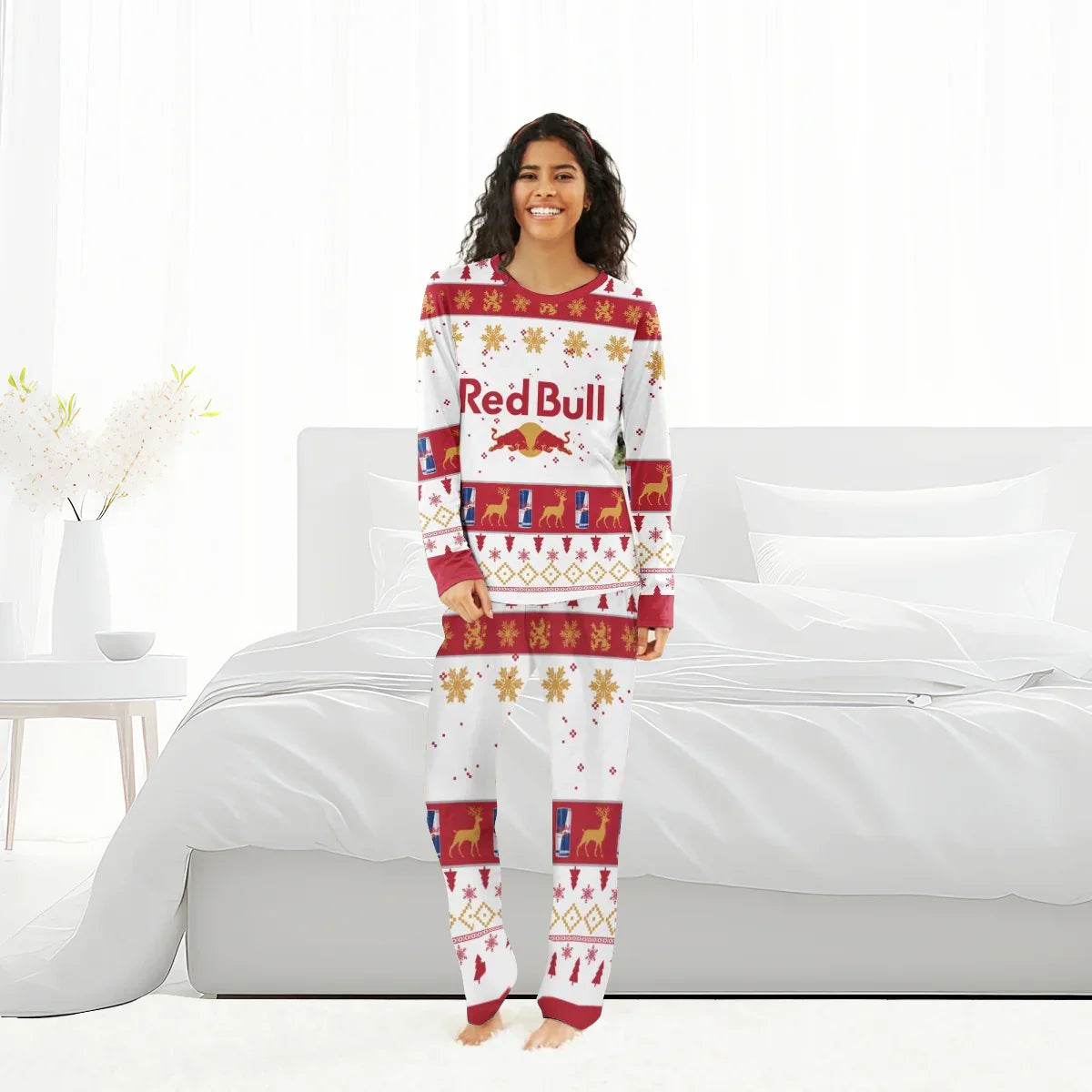 Smiling woman in Red Bull Christmas holiday pajamas with reindeer and snowflake patterns in bright bedroom