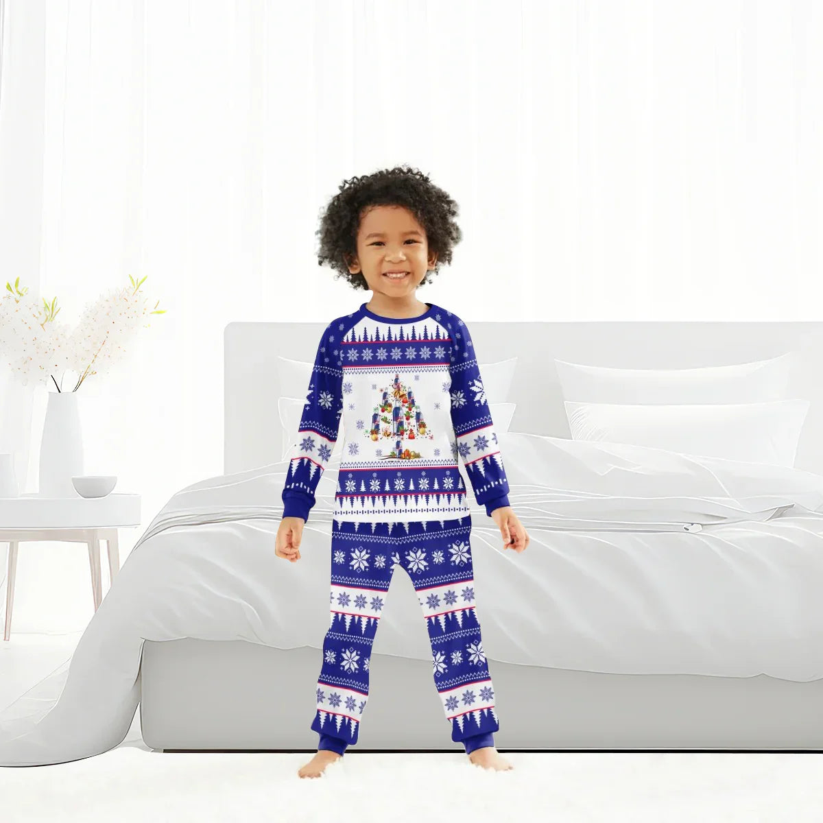 Smiling child in blue and white Christmas pajamas with snowflake and tree patterns in modern bedroom