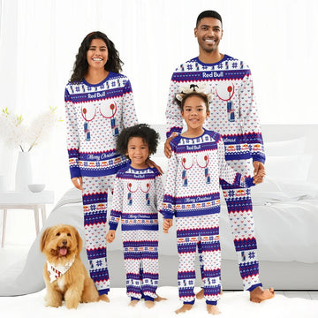 Smiling family in matching Red Bull Christmas pajamas standing barefoot indoors with fluffy dog