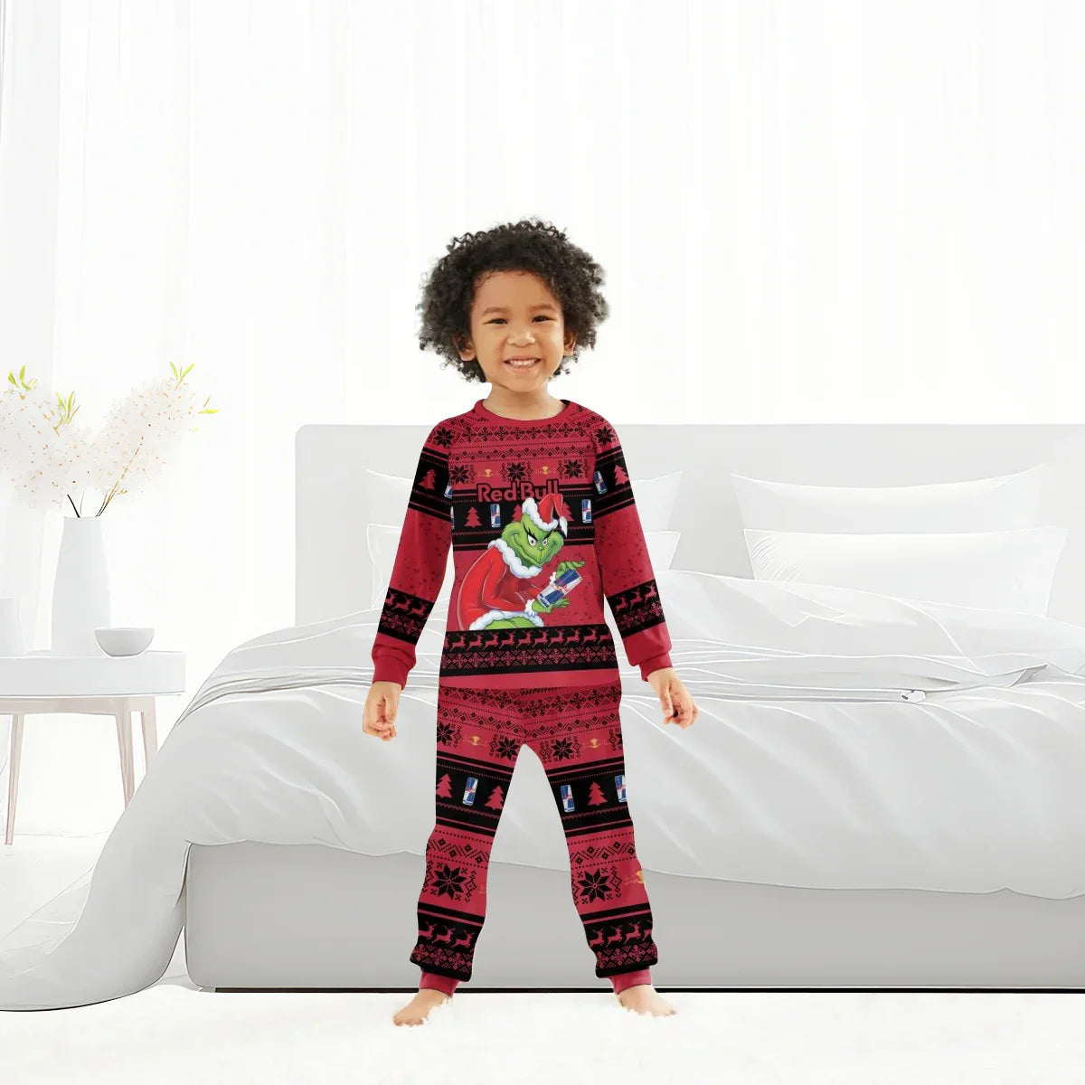 Smiling child in red Grinch and Red Bull themed Christmas pajamas in modern white bedroom