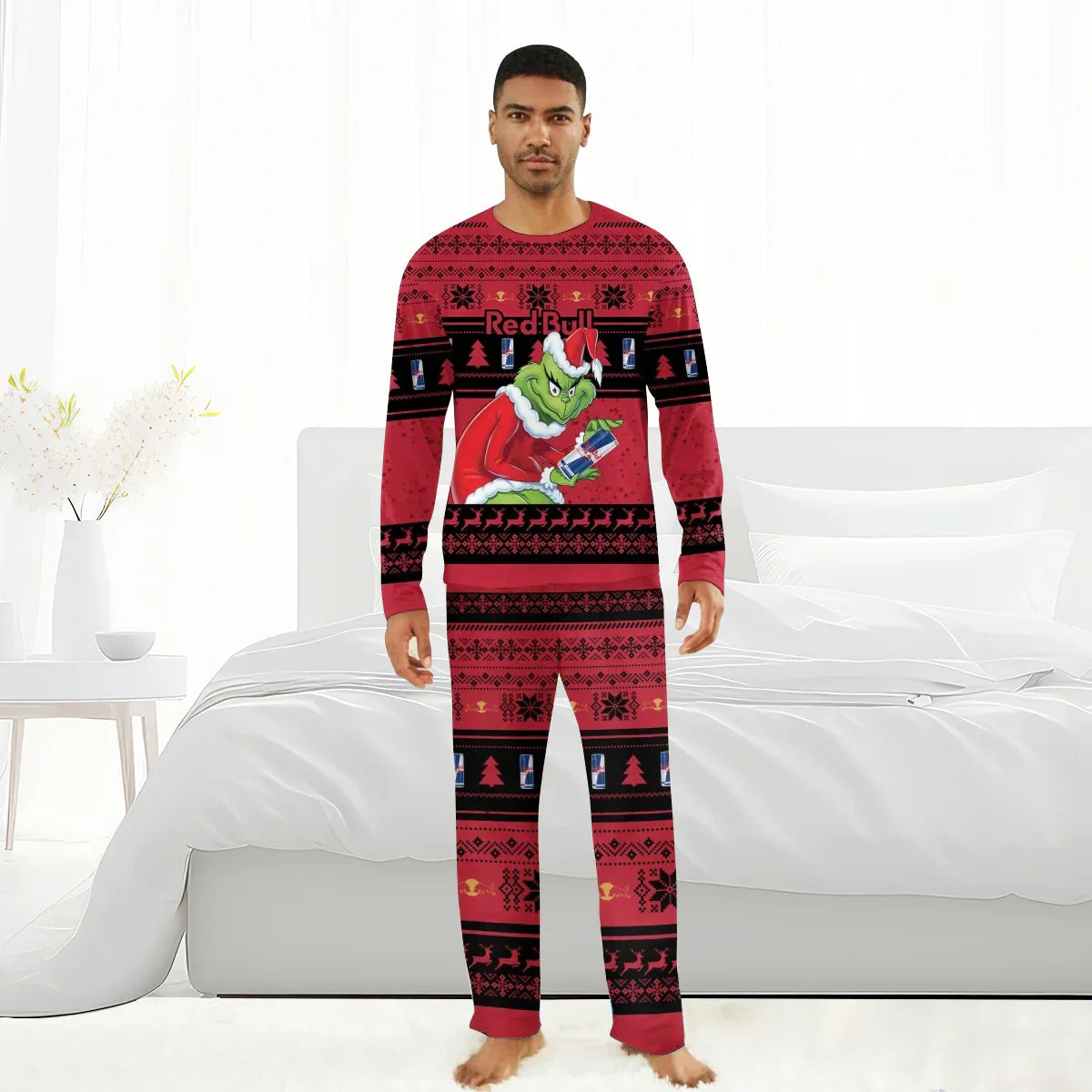 Man wearing red Christmas pajamas with Grinch and Red Bull design, standing barefoot in white bedroom