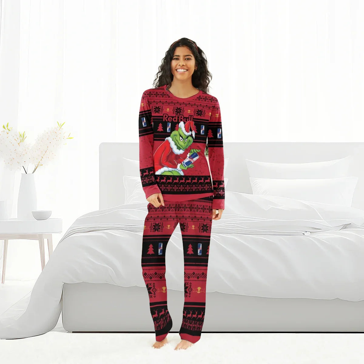 Smiling woman wearing Red Bull Grinch-themed Christmas pajama set in a bright bedroom