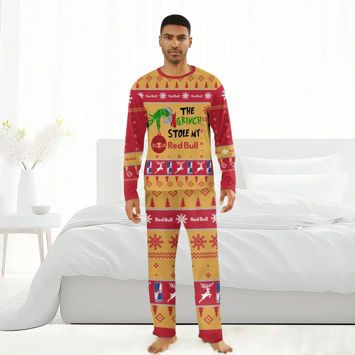 Man wearing red and gold Grinch-themed Christmas pajamas with Red Bull branding in a bright bedroom