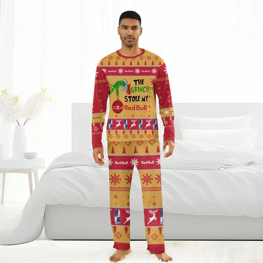 Man wearing red and gold Grinch-themed Christmas pajamas with Red Bull branding in a bright bedroom