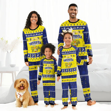 Family in matching blue and yellow Twisted Tea Christmas pajama sets standing in a bright bedroom with a dog
