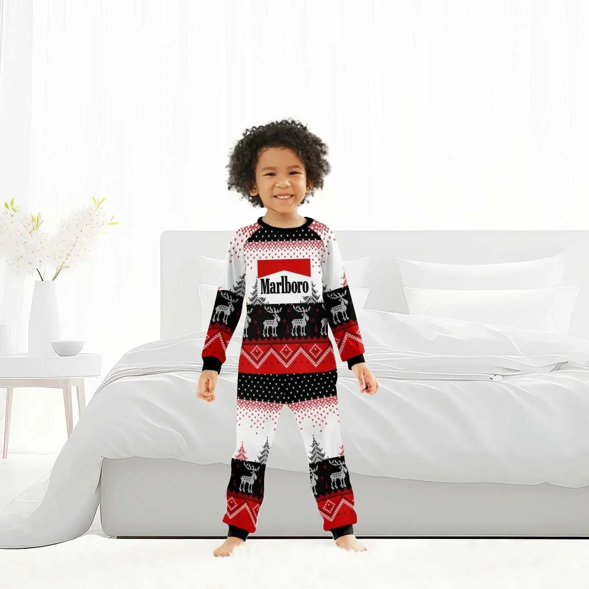Smiling child wearing red, black, and white Marlboro winter pajamas with reindeer pattern in modern bedroom