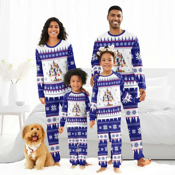 Smiling family in matching blue and white Christmas tree pajamas with snowflake patterns, with a dog wearing a holiday bandana